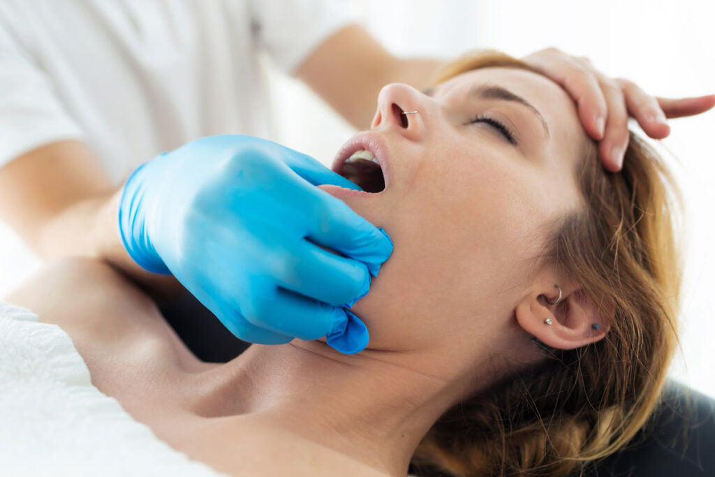 mujer recibiendo un masaje en la mandíbula por un fisioterapeuta