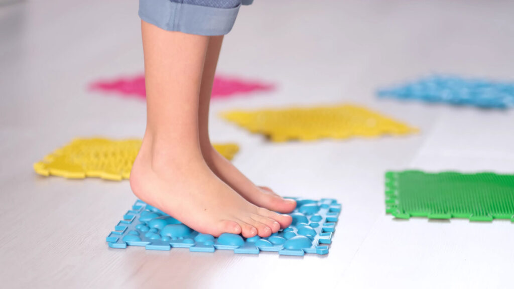 pies de un niño en una manta con relieve ortopédico de puntillas